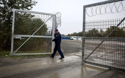 Illustrative: A Hungarian policeman closes a razor wire fence at a migrant transit center near Roszke, at the border crossing with Serbia, October 29, 2019. (Oliver Bunic/AFP)