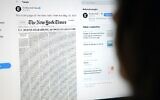 This picture from May 23, 2020, shows a woman looking at a computer screen with a tweet by the New York Times account showing the early edition front page of the newspaper for May 24, 2020 (Agustin Paullier/AFP)