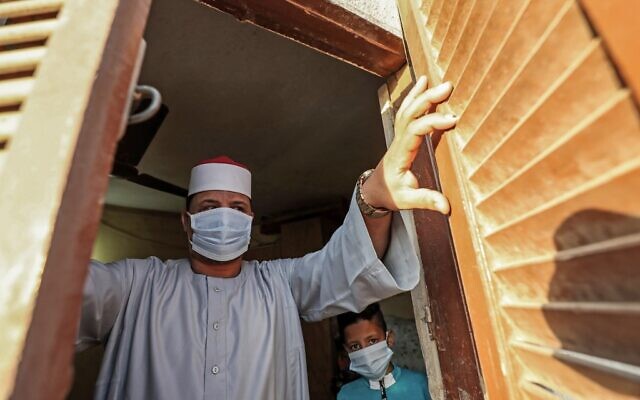 The Imam of a local mosque in the village of Shamma in Egypt's northern Nile delta province of Menoufia stands clad in mask due to the COVID-19 coronavirus pandemic by a window near the mosque early on May 24, 2020, before the prayers of Eid al-Fitr, the Muslim holiday which starts at the conclusion of the holy fasting month of Ramadan (Mohamed el-Shahed / AFP)