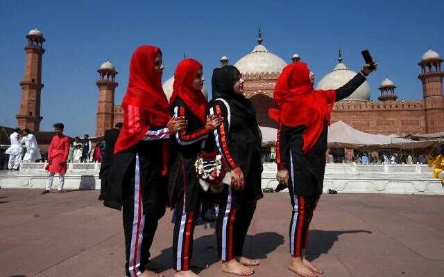 Muslim women take selfies after offering Eid al-Fitr prayers at the Badshahi Mosque in Lahore on May 24, 2020 (Arif ALI / AFP)