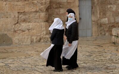 Three Catholic nuns wearing face masks stand in front of the Church of the Holy Sepulchre in Jerusalem's Old City as they await its reopening opening in Jerusalem, May 24, 2020. (Emmanuel Dunand/AFP)