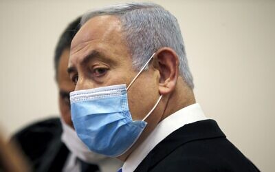 Prime Minister Benjamin Netanyahu, wearing a protective face mask, in the courtroom at the Jerusalem District Court on May 24, 2020, at the start of his corruption trial. (Ronen Zvulun/Pool/AFP)