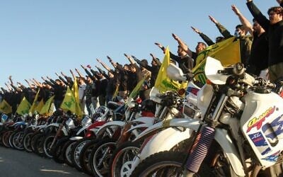 Supporters of the Lebanese terror group Hezbollah salute as they stand behind motorcycles carrying the Shiite movement's flags in the southern Lebanese district of Marjayoun on the border with Israel, May 25, 2020. (Mahmoud Zayyat/AFP)