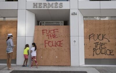 A family looks at a looted Hermes store on the iconic Rodeo Drive after demonstrators protested the death of George Floyd in Beverly Hills, California on May 31, 2020. (Mark RALSTON / AFP)