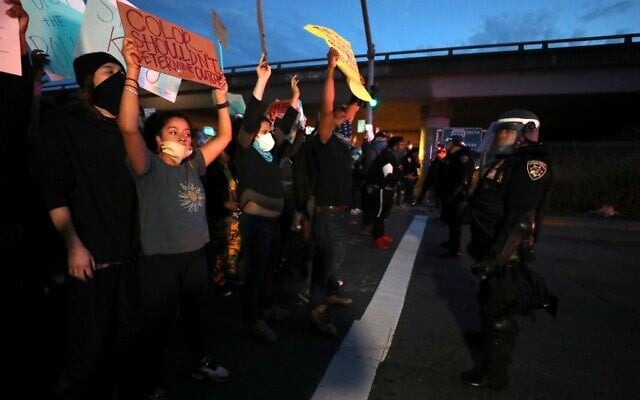Demonstrators holds hold signs in front of California Highway Patrol officers during a protest sparked by the death of George Floyd while in police custody on May 29, 2020 in Oakland, California (Justin Sullivan/Getty Images/AFP)