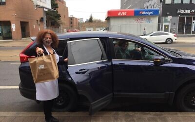 Judy Perly holds a takeout bag outside her Free Times Cafe. (Courtesy of Perly/ via JTA)