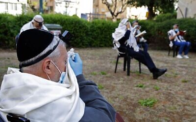 Jewish men pray while social distancing outside a closed synagogue in the coastal city of Netanya, April 23, 2020. (Jack Guez/AFP via Getty Images via JTA)