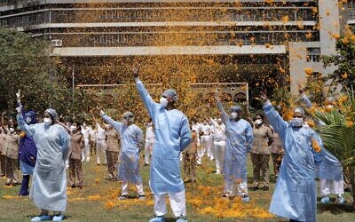 An Indian Air Force helicopter showers flower petals on the staff of INS Asvini hospital in Mumbai, India, Sunday, May 3, 2020. The event was part the Armed Forces' efforts to thank the workers, including doctors, nurses and police personnel, who have been at the forefront of the country's battle against the COVID-19 pandemic. (AP Photo/Rajanish Kakade)