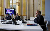 French President Emmanuel Macron, right, listens as he attends with French Foreign Minister Jean-Yves le Drian, center, an international videoconference on vaccination at the Elysee Palace in Paris, May 4, 2020. (Gonzalo Fuentes/Pool via AP)