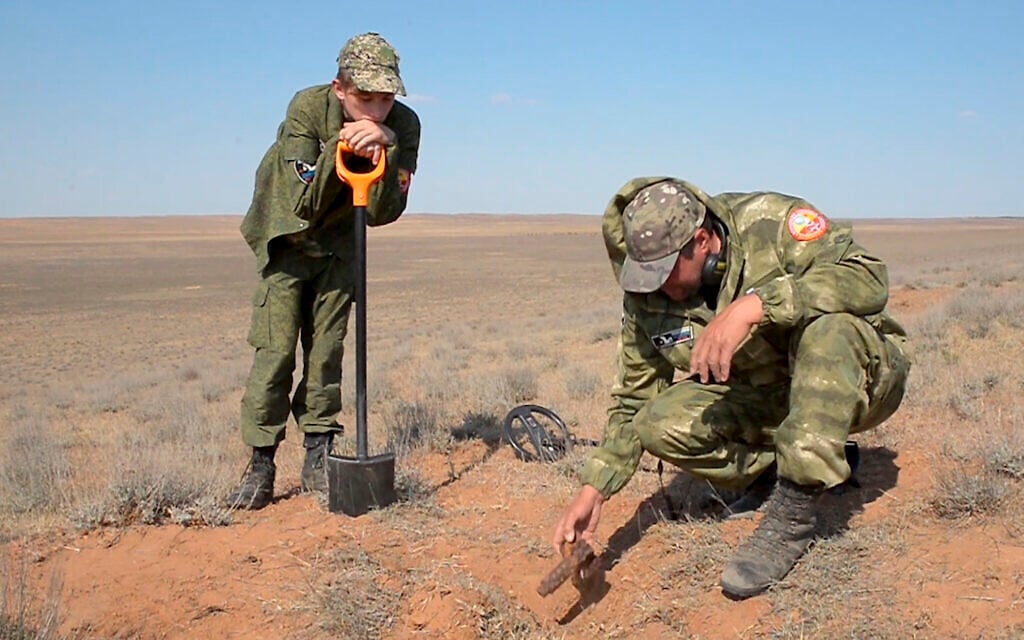 In this May 5, 2020 frame from video, Alfred Abayev, head of a volunteer group searching for remains of the WW II Red Army soldiers, right, looks at projectile left on a WW II battlefield near Khulkhuta in the province of Kalmykia in southern Russia. The search is part of a broad effort by myriad volunteer groups across the country to pay tributes to the fallen WW II soldiers. (AP Photo/Radik Nurmukhamedov) In this May 5, 2020 frame from video, Alfred Abayev, head of a volunteer group searching for remains of the WW II Red Army soldiers, right, looks at projectile left on a WW II battlefield near Khulkhuta in the province of Kalmykia in southern Russia. The search is part of a broad effort by myriad volunteer groups across the country to pay tributes to the fallen WW II soldiers. (AP Photo/Radik Nurmukhamedov)