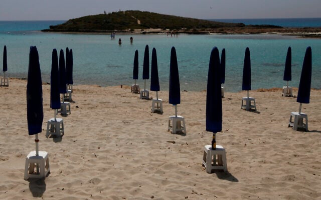 Rows of closed parasols on a nearly empty stretch of Nissi beach with a few beachgoers in the distance in Cyprus seaside resort of Ayia Napa, May 13 2020. (Petros Karadjias/AP) Rows of closed parasols on a nearly empty stretch of Nissi beach with a few beachgoers in the distance in Cyprus seaside resort of Ayia Napa, May 13 2020. (Petros Karadjias/AP)