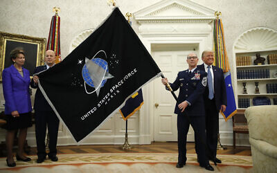 US President Donald Trump stands as Chief of Space Operations at US Space Force Gen. John Raymond, second from left, and Chief Master Sgt. Roger Towberman, second from right, hold the United States Space Force flag as it is presented in the Oval Office of the White House, May 15, 2020, in Washington.  Secretary of the Air Force Barbara Barrett stands far left. (AP Photo/Alex Brandon)