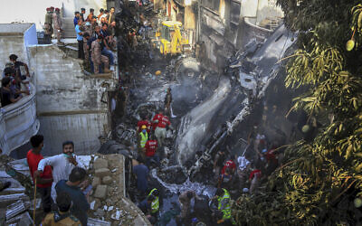 Volunteers look for survivors of a plane that crashed in a residential area of Karachi, Pakistan, May 22, 2020. (AP Photo/Fareed Khan)