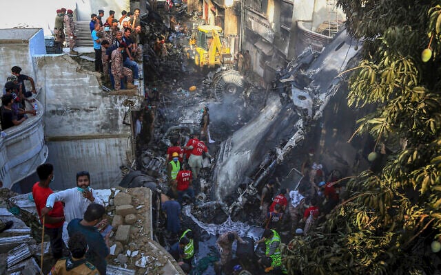 Volunteers look for survivors of a plane that crashed in a residential area of Karachi, Pakistan, May 22, 2020. (AP Photo/Fareed Khan) Volunteers look for survivors of a plane that crashed in a residential area of Karachi, Pakistan, May 22, 2020. (AP Photo/Fareed Khan)