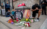 People gather and pray around a makeshift memorial, May 26, 2020, in Minneapolis, near the site where a black man, who was taken into police custody the day before, later died. (Elizabeth Flores/Star Tribune via AP)