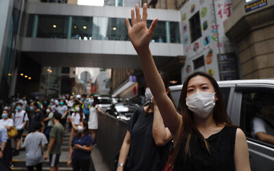 A protester gestures with five fingers, signifying the 'Five demands - not one less' during a protest in Central Government Complex in Hong Kong, May 27, 2020. (AP Photo/Kin Cheung)