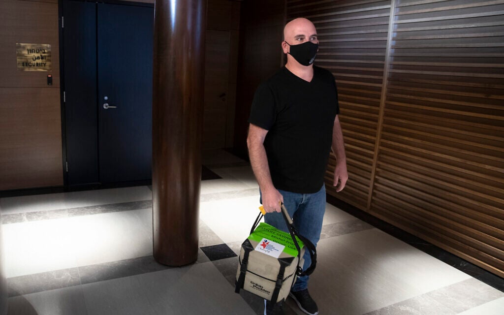 In this May 19, 2020, photo, Israeli courier, Mishel Zrian carries a bone marrow transplant donation at Ben Gurion airport near Tel Aviv, Israel. Over the past two months, as air travel has ground to a halt, Zrian has criss-crossed the Atlantic and the United States dozens of times, sleeping in empty airports and unable to return home to see his family in Israel, all in a race against time to deliver life-saving transplants. (AP Photo/Sebastian Scheiner) In this May 19, 2020, photo, Israeli courier, Mishel Zrian carries a bone marrow transplant donation at Ben Gurion airport near Tel Aviv, Israel. Over the past two months, as air travel has ground to a halt, Zrian has criss-crossed the Atlantic and the United States dozens of times, sleeping in empty airports and unable to return home to see his family in Israel, all in a race against time to deliver life-saving transplants. (AP Photo/Sebastian Scheiner)