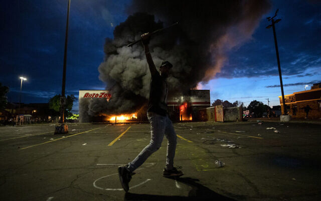 A man poses for a photo in the parking lot of an AutoZone store in flames, while protesters hold a rally for George Floyd in Minneapolis on Wednesday, May 27, 2020 (Carlos Gonzalez/Star Tribune via AP) A man poses for a photo in the parking lot of an AutoZone store in flames, while protesters hold a rally for George Floyd in Minneapolis on Wednesday, May 27, 2020 (Carlos Gonzalez/Star Tribune via AP)