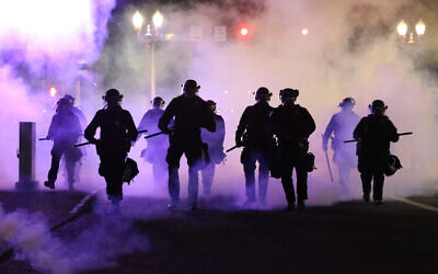 Police officers walk enveloped by teargas in Portland, Friday, March 29, 2020 (Dave Killen/The Oregonian via AP)