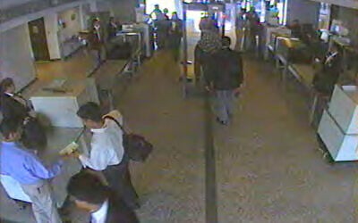 Hijackers Nawaf al-Hazmi, wearing a blue shirt, and his brother, Salem al-Hazmi, in the white shirt, wait at the security checkpoint at Dulles International Airport in Chantilly, Virginia on the morning of Sept. 11, 2001, as a screener checks Nawaf's carry-on bag for explosives This image was taken from surveillance video obtained by The Associated Press.  (AP Photo/APTN)