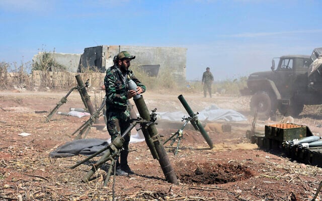Illustrative: Syrian army soldiers prepare to launch a mortar towards insurgents in the village of Kfar Nabuda, in the countryside of Hama province on May 11, 2019. (SANA via AP) Illustrative: Syrian army soldiers prepare to launch a mortar towards insurgents in the village of Kfar Nabuda, in the countryside of Hama province on May 11, 2019. (SANA via AP)