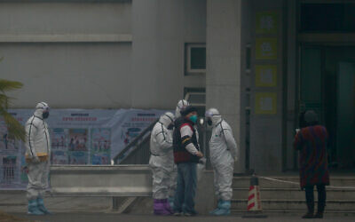 Staff in biohazard suits hold a metal stretcher by the in-patient department of Wuhan Medical Treatment Center, where some infected with a novel coronavirus are being treated, in Wuhan, China, Tuesday, Jan. 21, 2020. (AP Photo/Dake Kang)