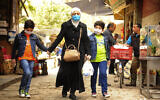 In this photo released on April 18, 2020, a Syrian woman walks with her sons wearing masks due to the coronavirus, in Damascus, Syria. (SANA via AP)