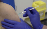 Screen grab taken from video issued by Britain's Oxford University, showing a person being injected as part of the first human trials in the UK to test a potential coronavirus vaccine, undertaken by Oxford University in England, on April 23, 2020. (Oxford University Pool via AP)