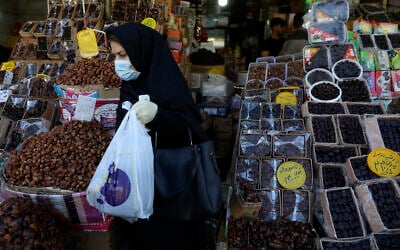 A woman wearing a protective face mask and gloves to help prevent the spread of the coronavirus carries her purchases as she leaves a store which sells dates, a favorite fruit for the Muslim holy fasting month of Ramadan, in Tehran on April 27, 2020. (AP Photo/Vahid Salemi) A woman wearing a protective face mask and gloves to help prevent the spread of the coronavirus carries her purchases as she leaves a store which sells dates, a favorite fruit for the Muslim holy fasting month of Ramadan, in Tehran on April 27, 2020. (AP Photo/Vahid Salemi)