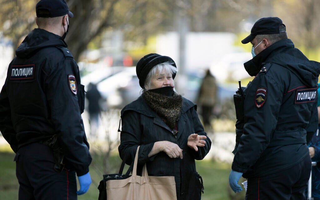 Russian police officers, wearing face masks to protect from coronavirus, speak to a woman as they check her documents to ensure a self-isolation regime due to coronavirus, in Moscow, Russia, April 28, 2020. (AP Photo/Alexander Zemlianichenko)