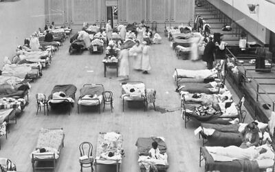 In this 1918 photo, volunteer nurses from the American Red Cross tend to influenza patients in the Oakland Municipal Auditorium, used as a temporary hospital. (Edward A. "Doc" Rogers/Library of Congress via AP)