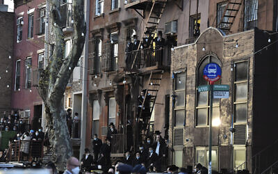 Residents of the Williamsburg neighborhood of the Brooklyn borough of New York stand on fire escapes as hundreds of mourners gather Tuesday, April 28, 2020, to observe a funeral for Rabbi Chaim Mertz, a Hasidic Orthodox leader whose death was reportedly tied to the new coronavirus. (Todd Maisel via AP)