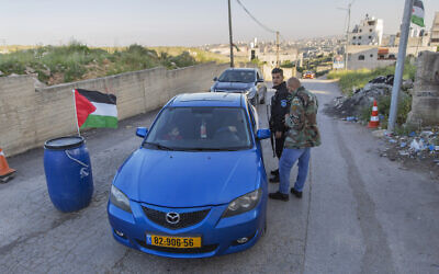 In this April 28, 2020 photo, Palestinian security forces stop vehicles, part of lockdown and quarantine measures to protect residents, at a checkpoint on an entrance to the West Bank village of Kafr Aqab, near Ramallah. (AP Photo/Nasser Nasser)