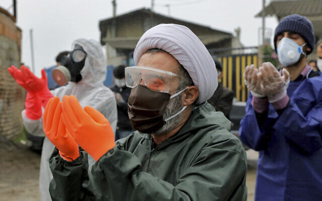 Mourners wearing protective clothing, face masks and gloves, pray over the body of a victim who died after being infected with the new coronavirus, in the outskirts of the Iranian city of Babol on April 30, 2020. (AP Photo/Ebrahim Noroozi) Mourners wearing protective clothing, face masks and gloves, pray over the body of a victim who died after being infected with the new coronavirus, in the outskirts of the Iranian city of Babol on April 30, 2020. (AP Photo/Ebrahim Noroozi)