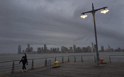 A woman wears a face mask as she walks on Pier 45 in Hudson River Park, April 30, 2020, in New York (AP Photo/Mark Lennihan)