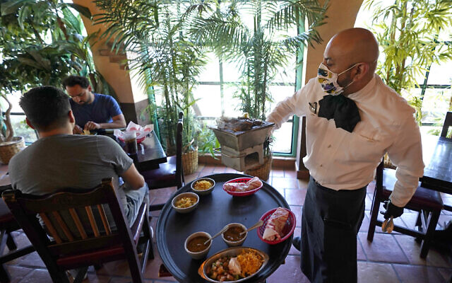 Waiter Marcos Huerta, right, serves a grill of fajitas at El Tiempo Cantina May 1, 2020, in Houston (AP Photo/David J. Phillip) Waiter Marcos Huerta, right, serves a grill of fajitas at El Tiempo Cantina May 1, 2020, in Houston (AP Photo/David J. Phillip)