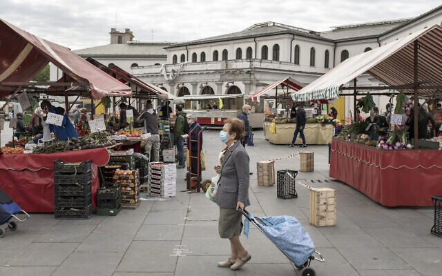 A woman wears a face mask as she pulls her shopping cart at the open air Porta Palazzo market, which reopened after two months of closure, in Turin, northern Italy, May 4, 2020 (Marco Alpozzi/LaPresse via AP) A woman wears a face mask as she pulls her shopping cart at the open air Porta Palazzo market, which reopened after two months of closure, in Turin, northern Italy, May 4, 2020 (Marco Alpozzi/LaPresse via AP)
