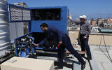 In this April 30, 2020, photo, Palestinian engineer Raed Nakhal from Palestine Children Relief Fund, right, and engineer Abdullah Dewik, check the Watergen machine that generates safe drinking water from air on the roof of al-Rantisi pediatric hospital in Gaza City. (AP Photo/Adel Hana)