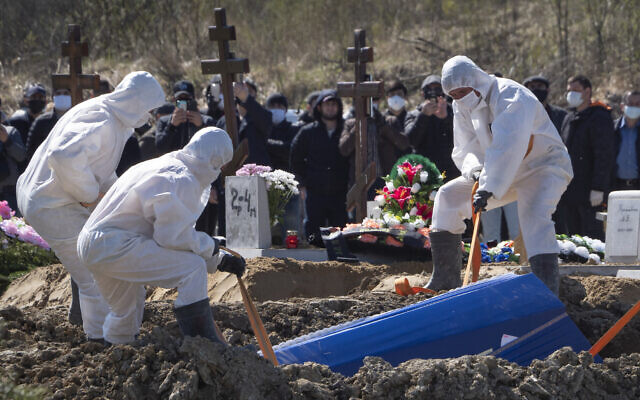 Gravediggers wearing protective suits bury a COVID-19 victim as relatives and friends stand at a safe distance, in the coronavirus section of a cemetery in Kolpino, outside St. Petersburg, Russia, May 10, 2020. (AP/Dmitri Lovetsky) Gravediggers wearing protective suits bury a COVID-19 victim as relatives and friends stand at a safe distance, in the coronavirus section of a cemetery in Kolpino, outside St. Petersburg, Russia, May 10, 2020. (AP/Dmitri Lovetsky)