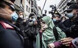 Silvia Romano, escorted by Carabinieri officers, arrives at her home wearing the green hijab typical of Somali Muslim women and a surgical mask to guard against COVID-19, in Milan, Italy, May 11, 2020. (AP Photo/Luca Bruno, File )