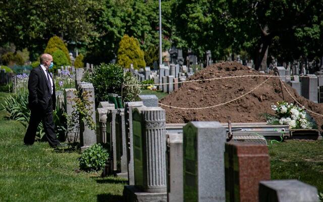 Robert Salerno, funeral director with McLaughlin & Sons funeral home in Brooklyn, wears a mask as he reviews a gravesite, shortly after a burial without family present because of coronavirus restrictions, May 13, 2020, at Holy Cross Cemetery in the Brooklyn borough of New York. (AP Photo/Bebeto Matthews) Robert Salerno, funeral director with McLaughlin & Sons funeral home in Brooklyn, wears a mask as he reviews a gravesite, shortly after a burial without family present because of coronavirus restrictions, May 13, 2020, at Holy Cross Cemetery in the Brooklyn borough of New York. (AP Photo/Bebeto Matthews)