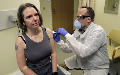 In this March 16, 2020, file photo, a pharmacist gives Jennifer Haller, left, the first shot in the first-stage safety study clinical trial of a potential vaccine for COVID-19, the disease caused by the new coronavirus, at the Kaiser Permanente Washington Health Research Institute in Seattle. The vaccine by Cambridge, Massachusetts-based Moderna Inc., generated antibodies similar to those seen in people who have recovered from COVID-19 in a study volunteers who were given either a low or medium dose. (AP Photo/Ted S. Warren, File)