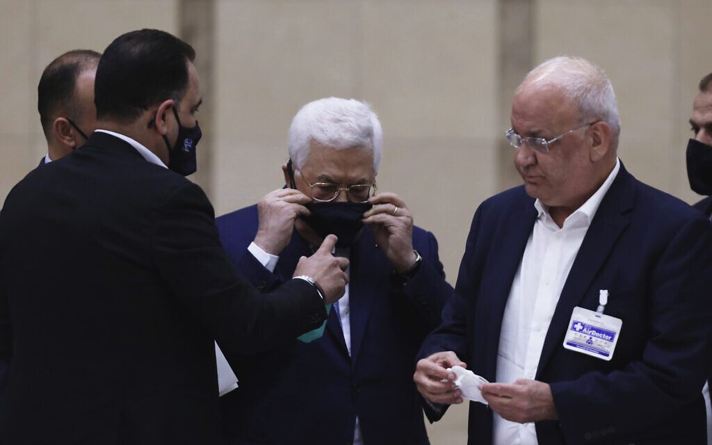 Palestinian Authority President Mahmoud Abbas puts on a face mask as he heads a leadership meeting at his headquarters in the West Bank city of Ramallah on May 19, 2020. (Alaa Badarneh/Pool Photo via AP)