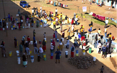 In this April, 24, 2020, photo, people wait to fetch water from a row of communal taps that the group Doctors Without Borders provided in a suburb of Harare, Zimbabwe  (AP Photo/Tsvangirayi Mukwazhi)