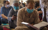 Palestinians wearing face masks read the Quran as they attend the last Friday noon Prayer of the holy month of Ramadan, in a mosque in Gaza City,  May. 22, 2020.  (AP Photo/Khalil Hamra)