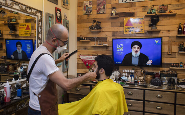 A barber wearing a mask to help stop the spread of the new coronavirus listens to a speech by Hezbollah leader Hassan Nasrallah being broadcast on Hezbollah's al-Manar TV channel, to mark Al-Quds (Jerusalem) day while he cuts a customer's hair at his salon, in the southern suburb of Beirut, Lebanon, Friday, May 22, 2020. (AP Photo/Hassan Ammar) A barber wearing a mask to help stop the spread of the new coronavirus listens to a speech by Hezbollah leader Hassan Nasrallah being broadcast on Hezbollah's al-Manar TV channel, to mark Al-Quds (Jerusalem) day while he cuts a customer's hair at his salon, in the southern suburb of Beirut, Lebanon, Friday, May 22, 2020. (AP Photo/Hassan Ammar)