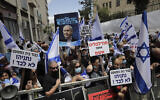 Right wing activists hold flags and signs in support of Prime Minister Benjamin Netanyahu during a demonstration outside the Jerusalem District Court, May 24, 2020 (AP Photo/Sebastian Scheiner)