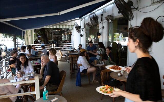 A waitress serves food at a restaurant in Tel Aviv, Israel, Wednesday, May 27, 2020. After more than two months of closure due to the coronavirus, restaurants in Israel were allowed to re-open Wednesday. (AP Photo/Sebastian Scheiner) A waitress serves food at a restaurant in Tel Aviv, Israel, Wednesday, May 27, 2020. After more than two months of closure due to the coronavirus, restaurants in Israel were allowed to re-open Wednesday. (AP Photo/Sebastian Scheiner)