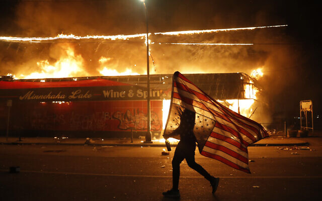 A protester carries a US flag upside down, a sign of distress, next to a burning building Thursday, May 28, 2020, in Minneapolis (AP Photo/Julio Cortez) A protester carries a US flag upside down, a sign of distress, next to a burning building Thursday, May 28, 2020, in Minneapolis (AP Photo/Julio Cortez)