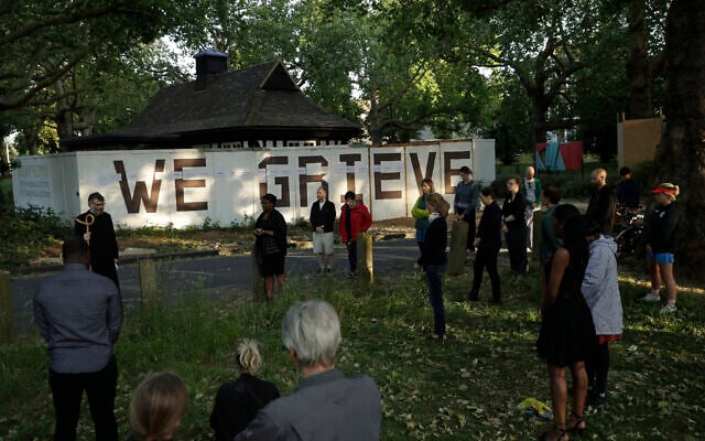 Reverend William Taylor, top left, and local people standing with social distancing observe a 30 second silence during a remembrance event as they add the names of five people who recently died to the community "We Grieve" wall at Clapton Common, in London, May 28, 2020 (AP Photo/Matt Dunham) Reverend William Taylor, top left, and local people standing with social distancing observe a 30 second silence during a remembrance event as they add the names of five people who recently died to the community "We Grieve" wall at Clapton Common, in London, May 28, 2020 (AP Photo/Matt Dunham)